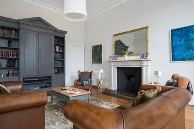 a living room with leather furniture and a fireplace at Magnificent Georgian 3-Bedroom Apartment in New Town in Edinburgh