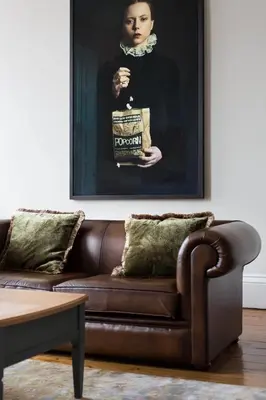 a brown couch in a living room with a picture of a woman at Magnificent Georgian 3-Bedroom Apartment in New Town in Edinburgh