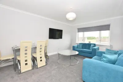 a living room with a blue couch and a table at Lovely 2 Bedroom Flat in a quiet location in Airdrie