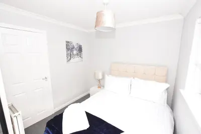 a bedroom with white walls and a bed with white pillows at Lovely 2 Bedroom Flat in a quiet location in Airdrie