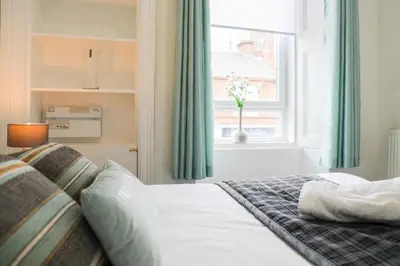 a bedroom with a bed and a window with a vase of flowers at Glasgow, Bothwell, 3 bed, Suitable for Long Stays in Bothwell