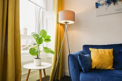 a living room with a blue couch and a plant at Glasgow, Bothwell, 3 bed, Suitable for Long Stays in Bothwell