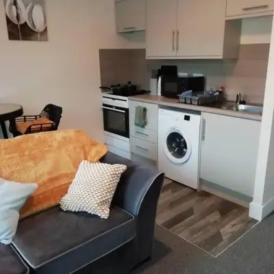 a kitchen with a couch and a washing machine in it at Carvetii - Norman House - 2nd floor, 1 bedroom flat in Boʼness