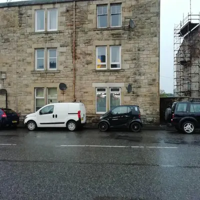 two cars parked in front of a brick building at Carvetii - Norman House - 2nd floor, 1 bedroom flat in Boʼness