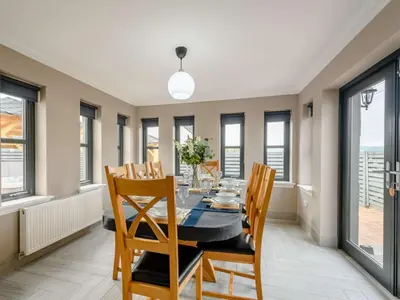 a dining room with a table and chairs and windows at Westertonhill Lodge - 3 Double Bedrooms Sleeps 8 With Private Hot Tub Hire Available in Balloch