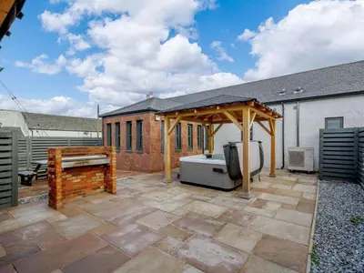 a patio with a gazebo next to a building at Westertonhill Lodge - 3 Double Bedrooms Sleeps 8 With Private Hot Tub Hire Available in Balloch