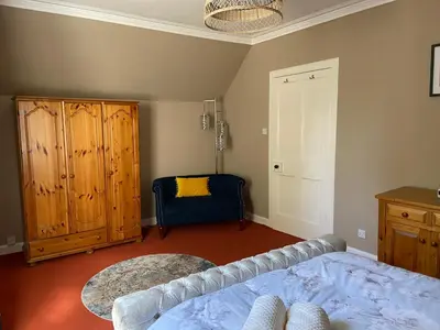 a bedroom with a bed and a cabinet and a chair at Fabulous 2 Bedroom House just outside Edinburgh in Auchendinny