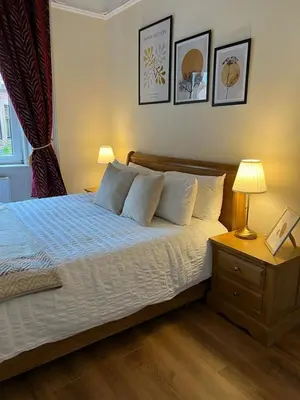 a bedroom with a bed and a table with a lamp at Victorian 3 BR main door flat, King size beds , large rooms in Glasgow