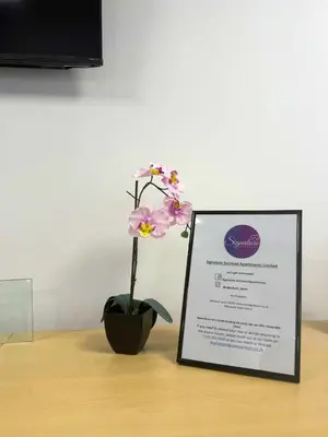 a flower in a vase sitting next to a sign at Signature - Linden House Flat 1 in Airdrie