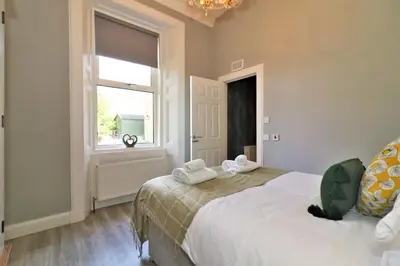 a bedroom with a large bed and a window at Signature - Linden House Flat 1 in Airdrie