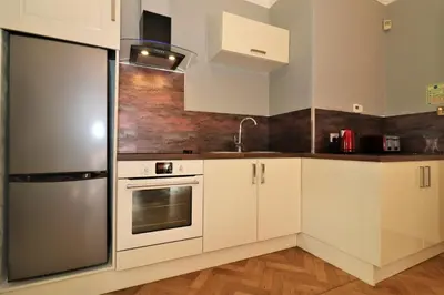 a kitchen with white cabinets and a stainless steel refrigerator at Signature - Linden House Flat 1 in Airdrie