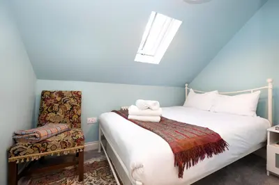 a bedroom with a white bed and a chair at JOIVY Inviting Flat at the Heart of Edinburgh in Edinburgh
