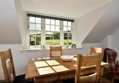 a dining room with a wooden table and a window at The Studio at Pitmeadow Farm in Dunning