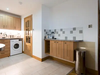 a kitchen with wooden cabinets and a washer and dryer at Beautiful Unique 3Bed Mews Cottage House - Pass the Keys in Glasgow