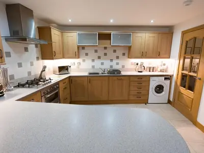 a kitchen with wooden cabinets and a washer and dryer at Beautiful Unique 3Bed Mews Cottage House - Pass the Keys in Glasgow