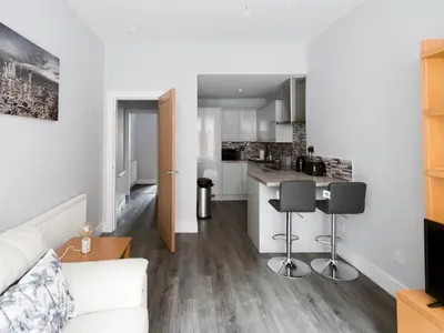 a living room with a white couch and a kitchen at Superb 1Bed Flat in Fabulous West End - Pass the Keys in Glasgow