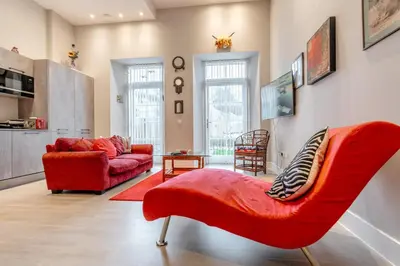a living room with a red chair and a couch at Unique Two Bed Holiday Home in Edinburgh in Edinburgh