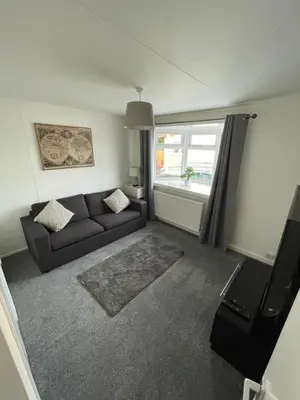 a living room with a couch and a window at 1-Bedroom Chalet at Maryville Caravan Site - Uddingston, Glasgow in Uddingston