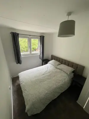 a bedroom with a white bed and a window at 1-Bedroom Chalet at Maryville Caravan Site - Uddingston, Glasgow in Uddingston