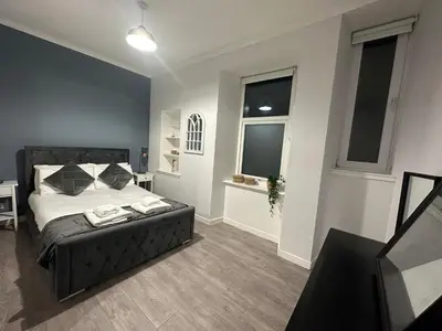 a bedroom with a bed and two windows at One bedroom flat in Oban town centre in Oban