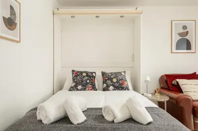 a bedroom with a bed with white sheets and pillows at Central Studio Near Usher Hall & Edinburgh Castle in Edinburgh