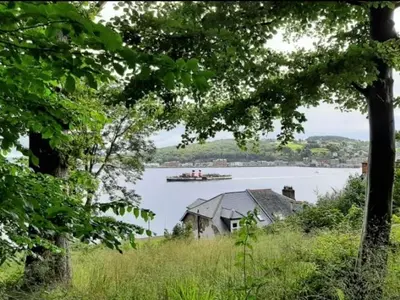 a boat on a lake with a house and a house at Dairsie Sea View in Rothesay