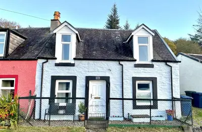 a white brick house with a black roof at Chapelton Cottage in Strachur