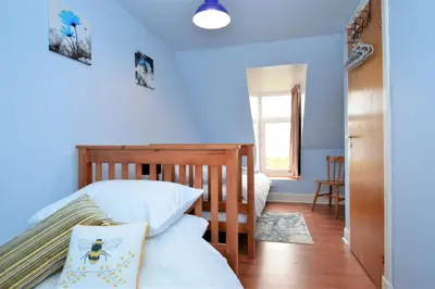 a bedroom with blue walls and a bed with white pillows at Chapelton Cottage in Strachur
