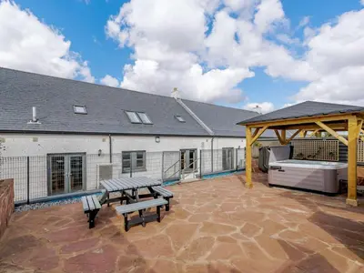 a patio with two benches and a picnic table at Westertonhill Lodge - 4 Bedrooms Sleeps 10 with Private Hot Tub Hire Available in Balloch