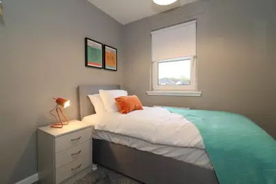a small bedroom with a bed and a window at Signature - Carnbroe House in Old Monkland