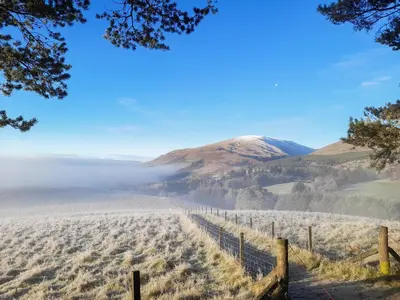 a fence in a field with a mountain in the background at Devin Lodge in Dollar