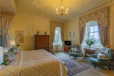 a bedroom with a bed and a chair and a dresser at Glenapp Castle in Ballantrae