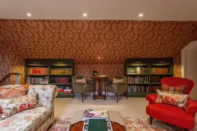a living room with a couch and chairs and bookshelves at Glenapp Castle in Ballantrae