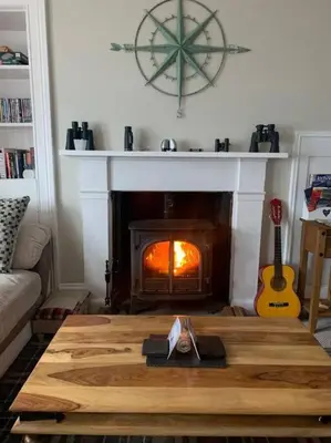 a living room with a fireplace and a wooden table at Superb Loch Side Apartment with Sea & Sunset Views in Helensburgh