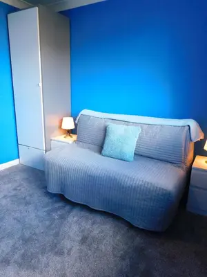 a bedroom with a bed with a blue wall at Charming 2 bed house Perfect base for sightseeing in Johnstone