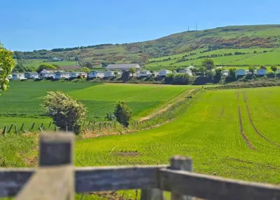 a view of a green field with houses on a hill at Heads Of Ayr Holiday Park in Ayr