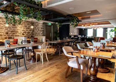 a restaurant with tables and chairs and a brick wall at The Raeburn in Edinburgh