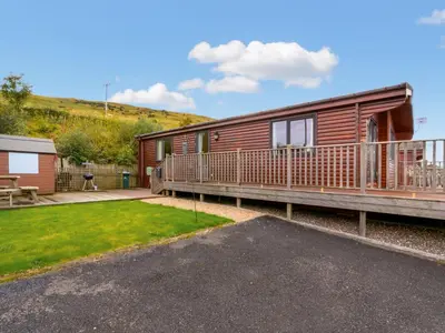 a wooden cabin with a deck and a patio at Chalet Lodge 9 by Interhome in Kinross
