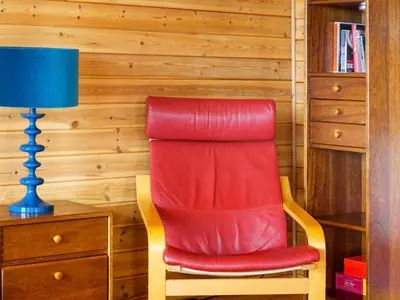 a red chair sitting next to a desk with a blue lamp at Chalet Lodge 9 by Interhome in Kinross