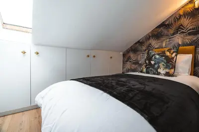 a bedroom with a bed with a black blanket on it at The West End Loft - 5* Retreat - Private Parking! in Glasgow