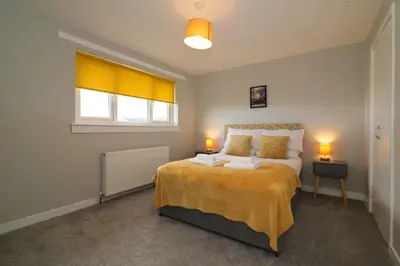 a bedroom with a bed and two lamps and a window at Signature - Sydney House in East Kilbride