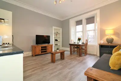a living room with a television and a table at Signature - Linden House Flat 4 in Airdrie