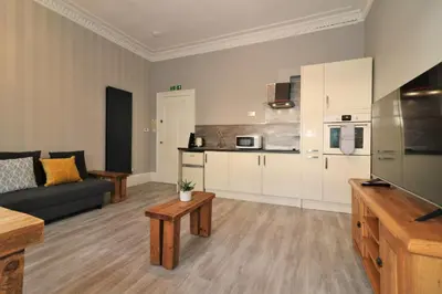a living room with a couch and a kitchen at Signature - Linden House Flat 4 in Airdrie
