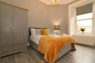a bedroom with a bed with an orange blanket at Signature - Linden House Flat 4 in Airdrie