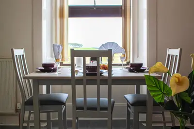 a dining room table with four chairs and a window at Station Signature Apartment near Lanark in Carstairs
