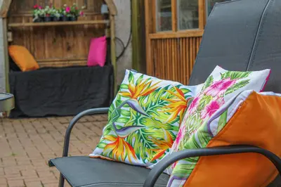 a black chair with two colorful pillows on it at Station Signature Apartment near Lanark in Carstairs