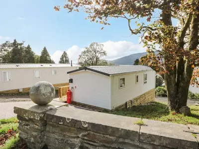 a home with a stone wall and a building at 11 Mansion View in Helensburgh