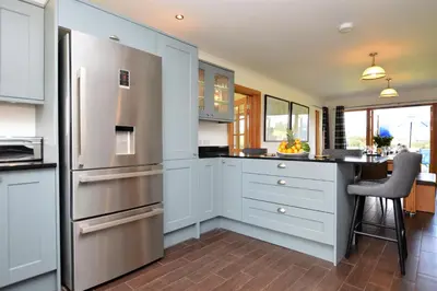 a kitchen with white cabinets and a stainless steel refrigerator at Kennacraig Lodge in Whitehouse