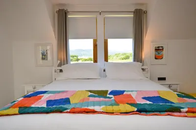a bed with a colorful quilt on it with a window at Kennacraig Lodge in Whitehouse