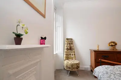 a bedroom with a fireplace and a chair next to a bed at Glen Oirig in Hunters Quay